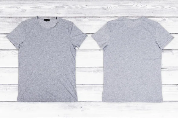 Two gray blank T-shirts on a white wooden background — Stock Photo, Image