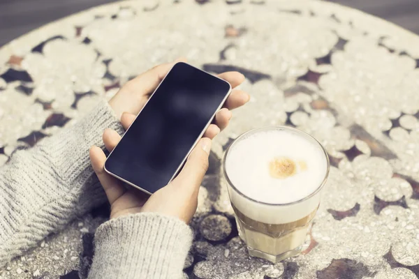 Menina com telefone celular em branco e xícara de café — Fotografia de Stock