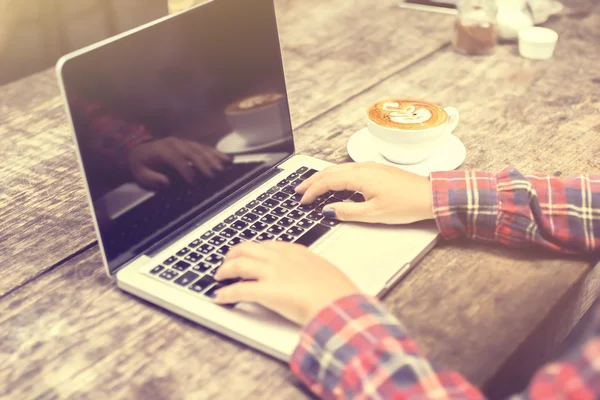 Mulher digitando em um laptop com uma xícara de café ao nascer do sol — Fotografia de Stock