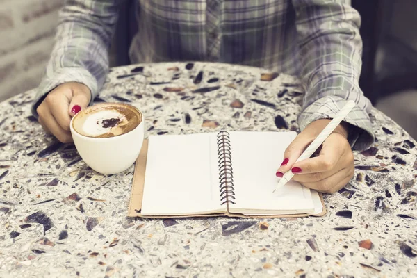 Chica haciendo notas y bebiendo café — Foto de Stock