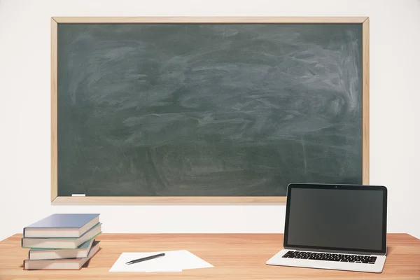 Schoolbord, houten tafel, boeken en laptop — Stockfoto