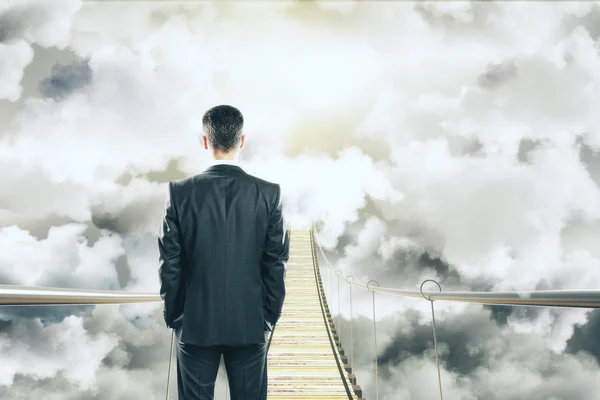 Бізнесмен йде по повітряному мосту серед концепції хмар — стокове фото