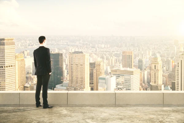 Empresario en la cima del edificio y mirando a la ciudad — Foto de Stock