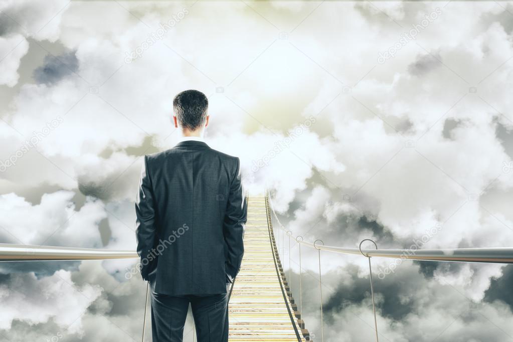 Businessman is walking on air bridge among the clouds concept