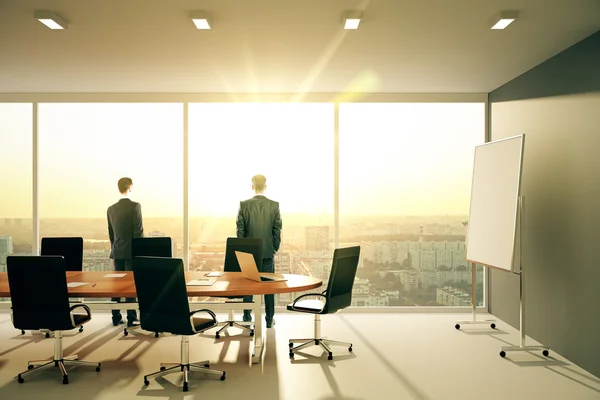 Businessmen in sunny conference room with furniture and cityview — Stock Photo, Image