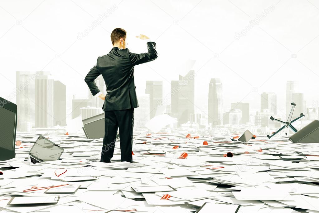 Businessman is looking at the horizont among pile of papers and