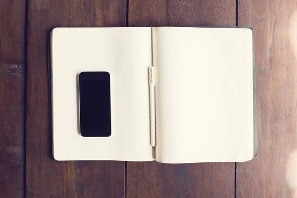 Leere Smartphone-Desktop auf leere Seiten des Tagebuchs mit Stift auf woo — Stockfoto