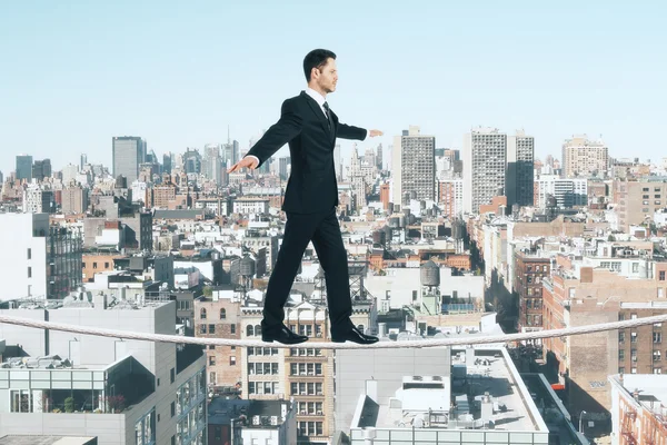 Бизнесмен идет по веревке на фоне города — стоковое фото
