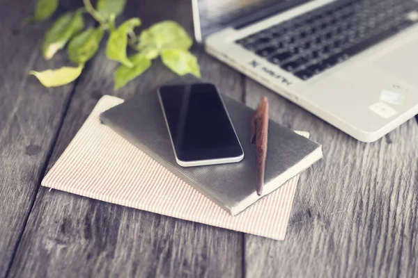 Smartphone, journal, stylo et ordinateur portable sur une table en bois extérieure — Photo