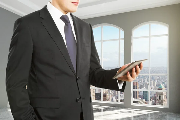 Businessman looking at digital tablet in empty loft room — Stock Photo, Image