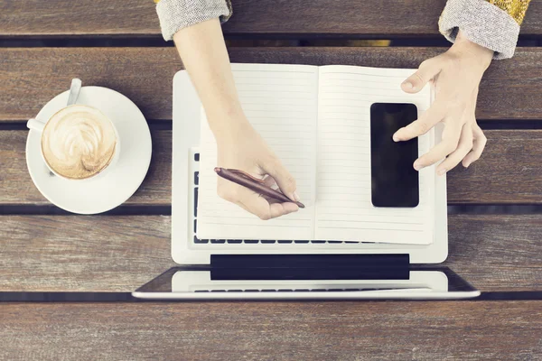 Mädchen mit Laptop, leerem Tagebuch, Handy und Kaffeebecher auf Holz — Stockfoto