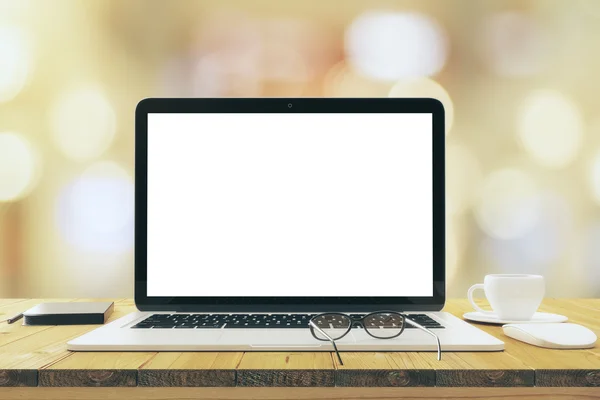 Pantalla blanca en blanco del ordenador portátil en la mesa de madera con los anteojos y el cu — Foto de Stock