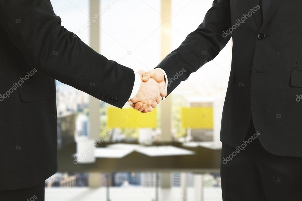 Businessmen shake hands in office