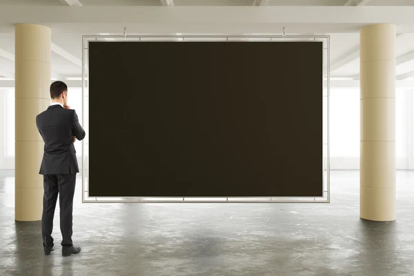 日当たりの良い広々 とした格納庫で空の黒板を見て実業家 — ストック写真