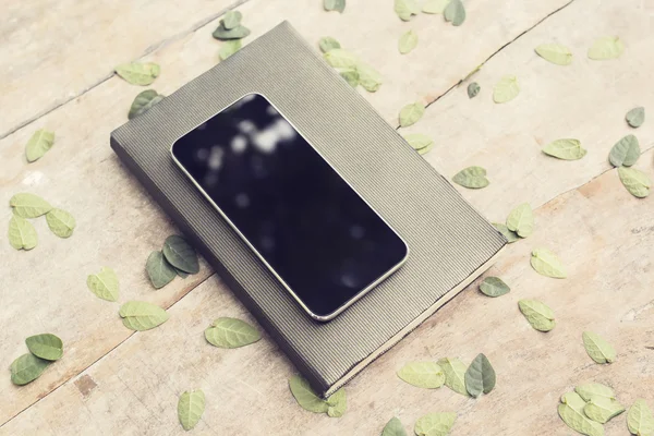 空白的黑色智能手机屏幕上日记与木选项卡上的叶子 — 图库照片