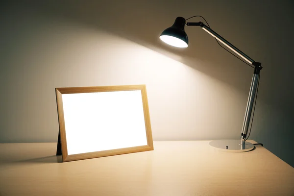 Leerer Bilderrahmen mit Lampe auf Holztisch, Attrappe — Stockfoto