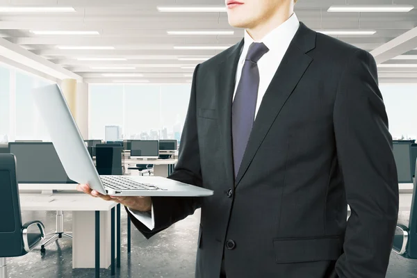 Biznesmen patrząc mu laptopa w nowoczesnej, otwartej przestrzeni biura — Zdjęcie stockowe