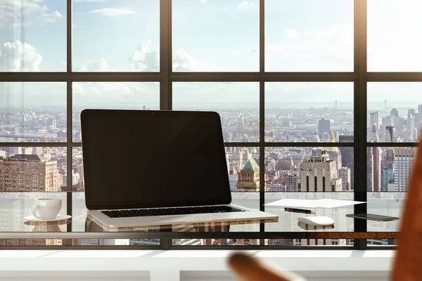 Blank laptop on a glass table in a modern office and city views — Stock Photo, Image