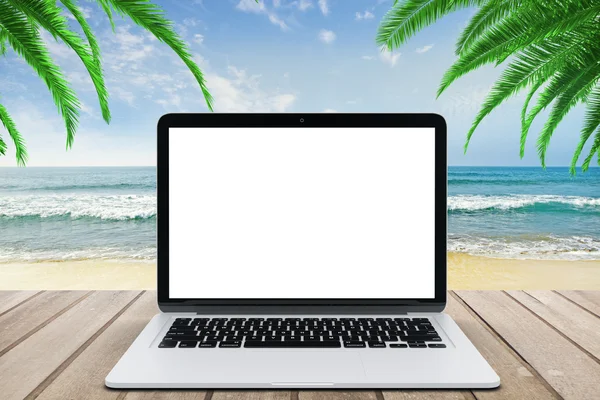 Tela de laptop branco em branco no banco de madeira no fundo da praia — Fotografia de Stock