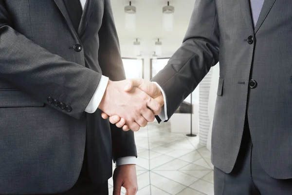 Two businessman shaking hands in a light modern office — Stock Photo, Image