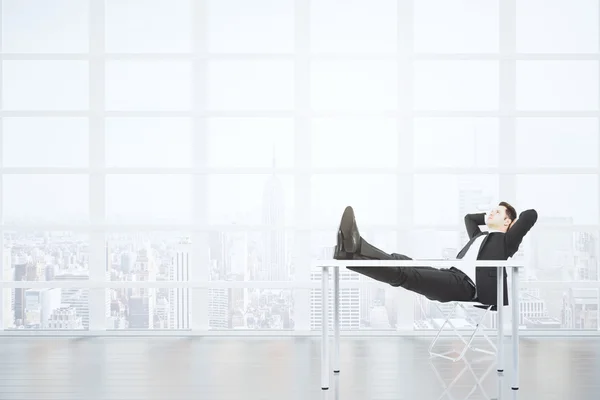 Bsuinessman resting on a chair in empty spacious loft room with