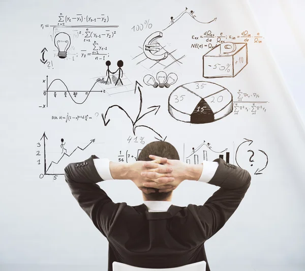 Businessman sitting on a chair and looking at white wall with bu — Stock Photo, Image