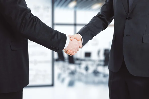 Zakelijke partners schudden handen in moderne conferentieruimte — Stockfoto