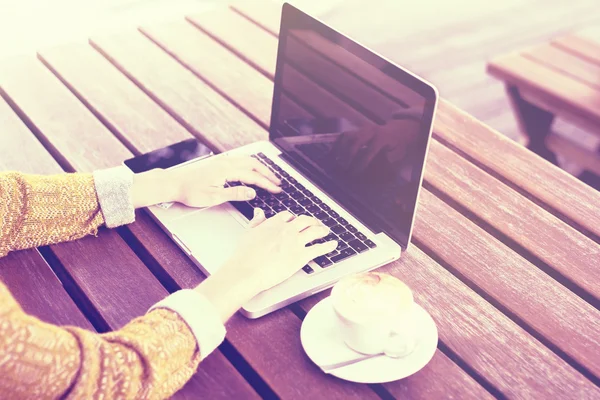 Хіпстерська дівчина з ноутбуком, чашкою кави та смартфоном на відкритому повітрі — стокове фото