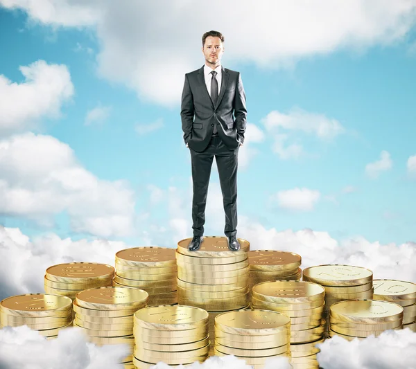 Podnikatel na hromady zlatých mincí na mraky t modré s — Stock fotografie