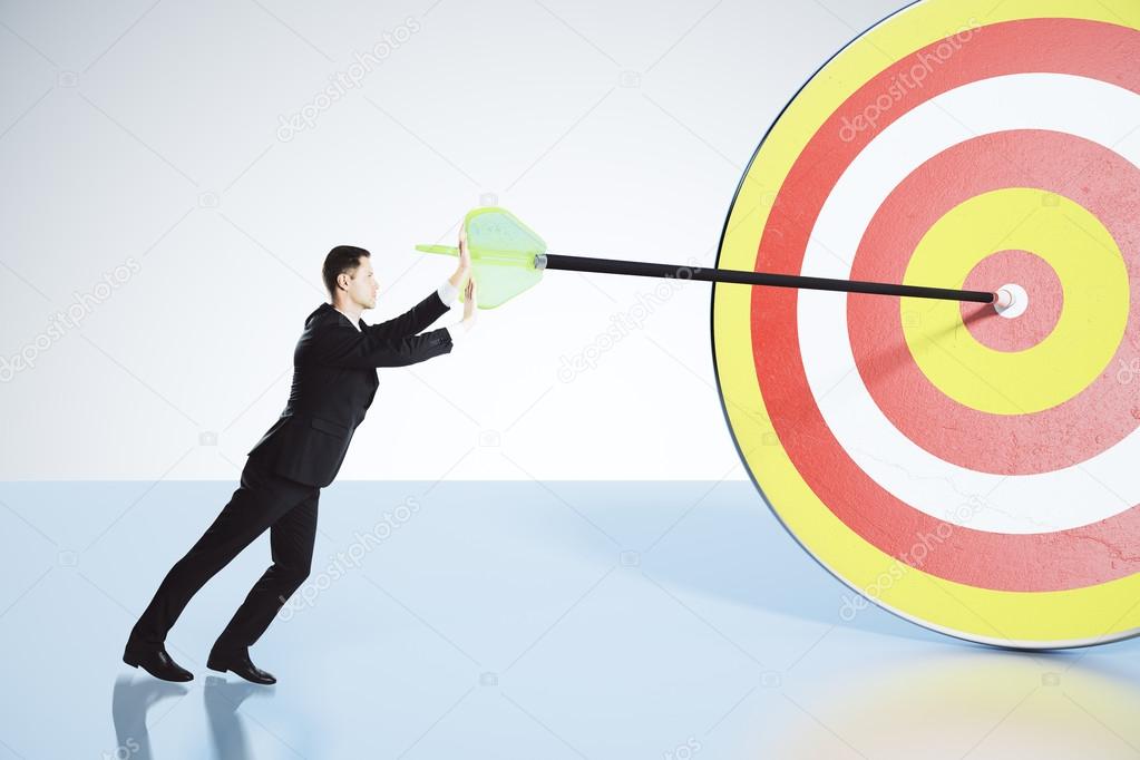 Businessman pushes arrow exactly in bull's-eye concept