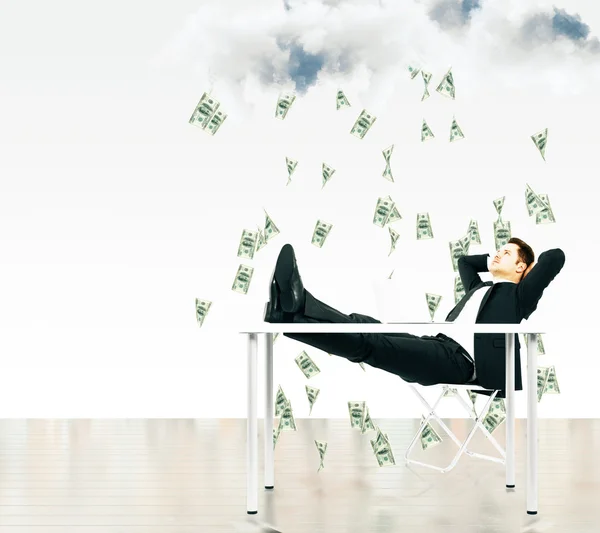 Деньги падают с неба концепции с бизнесменом, сидящим на — стоковое фото