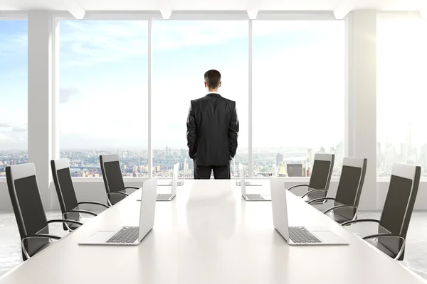 Geschäftsmann steht im Konferenzraum und schaut aus dem Fenster — Stockfoto