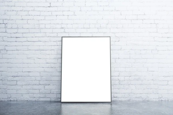 Blank white picture frame on concrete floor in empty room with w — Stock Photo, Image