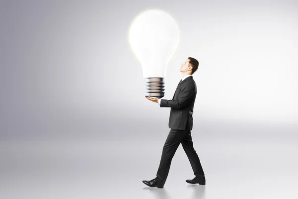 Ideia conceito com empresário carrega grande lâmpada — Fotografia de Stock