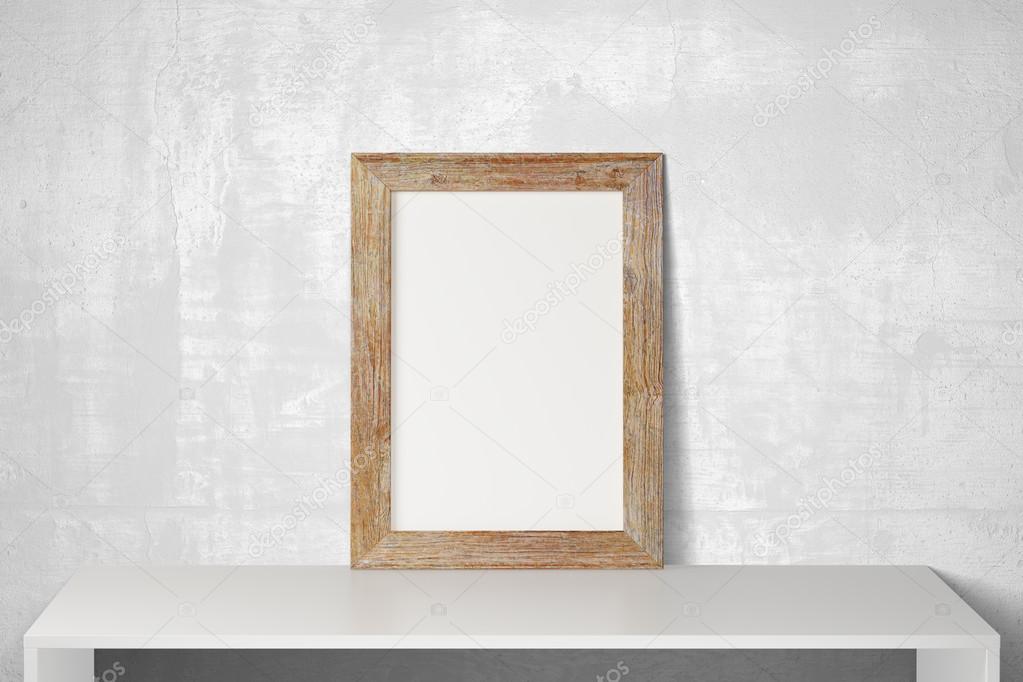 Blank wooden picture frame on white table and concrete floor, mo