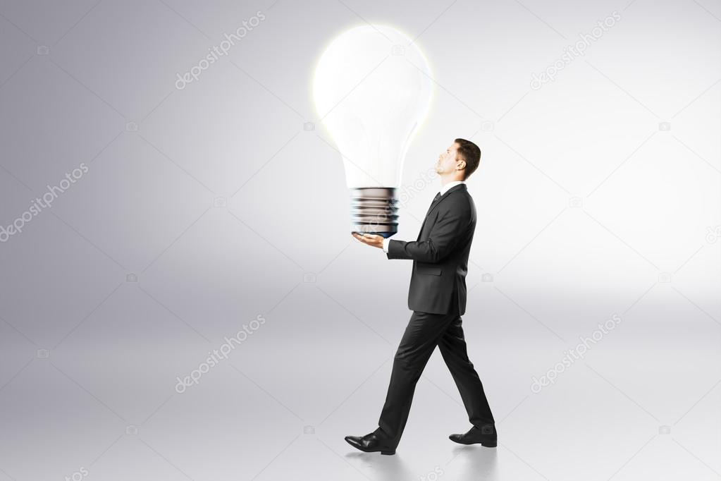 Idea concept with businessman carries big light bulb