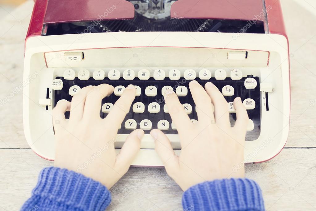 Girl with old style typewriter on the wooden table