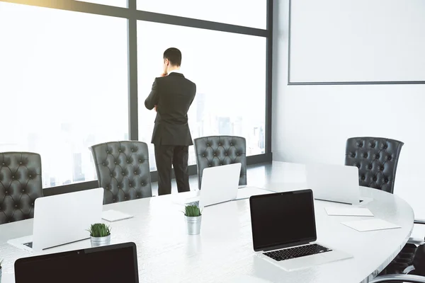 Empresario piensa y mira por la ventana grande en la sala de conferencias w — Foto de Stock