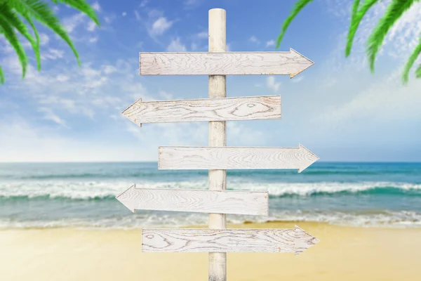 Witte houten pijlen-pointers in ocean met beach achtergrond — Stockfoto