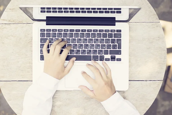 Hombre manos escribiendo con el ordenador portátil en la mesa de madera — Foto de Stock