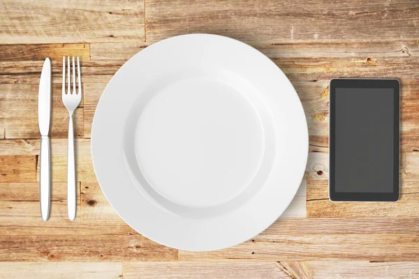 Placa e telefone celular em uma mesa de madeira — Fotografia de Stock