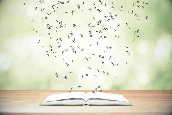 Flygande bokstäver från öppnade boken på träbord — Stockfoto
