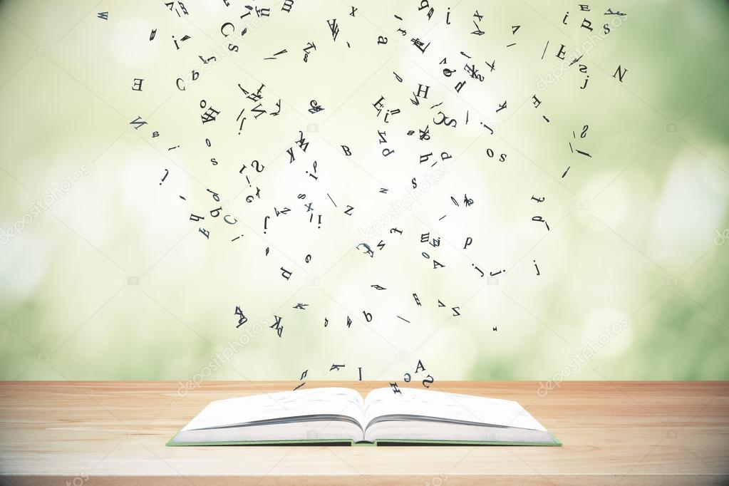 Flying letters from the opened book on wooden table