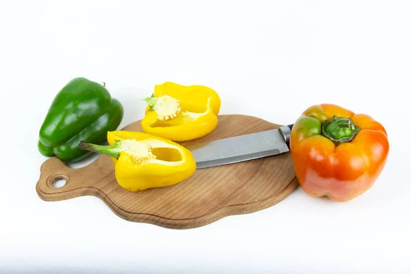 新鮮な野菜 黄色のピーマンは 緑色の茎とナイフで半分に切断され 孤立した白い背景に切断板に横たわっています 上からの眺め 新鮮な野菜 — ストック写真