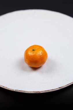 Siyah arka planda, mandalinalı büyük desenli bir tabak..