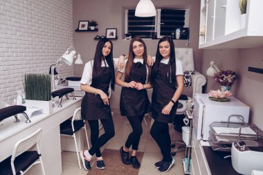 İş yerindeki mutlu profesyonel manikürcülerin portresi kuaföre davet ediliyor. Özel üniformalı profesyonel manikürcü bir güzellik salonunda çalışıyor.