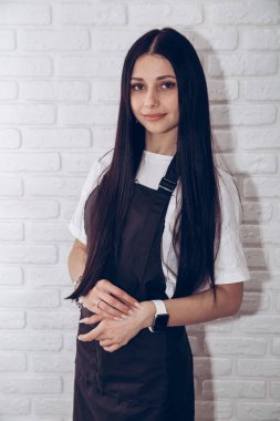 Beyaz tuğlalı arka planda esmer bir kız. Mesaj ve logo için yeri var.