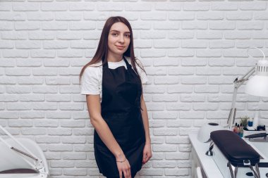 Beyaz tuğlalı arka planda esmer bir kız. Mesaj ve logo için yeri var.