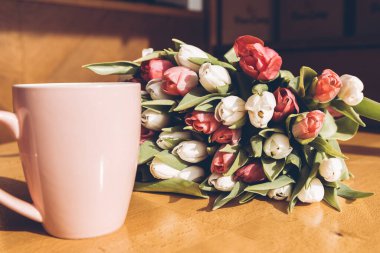 Anneler Günün kutlu olsun. Bir fincan kahve ve masanın üzerinde bir buket beyaz ve kırmızı laleler.