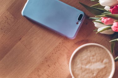 Anneler Günün kutlu olsun. Bir fincan kahve ve masanın üzerinde bir buket beyaz ve kırmızı laleler.